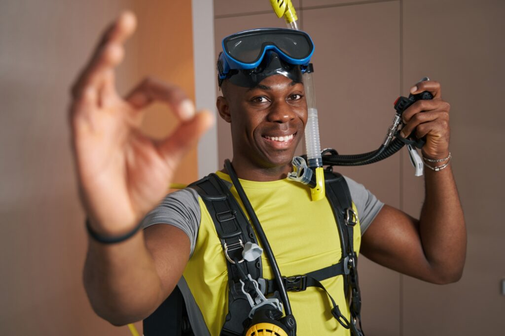 Joyful scuba diver in room showing ok gesture